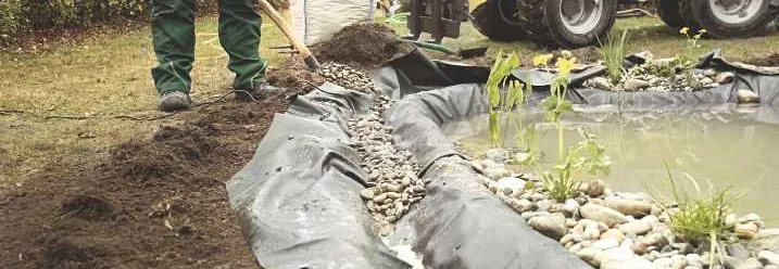 Person beim Anlegen eines Teichs mit Schaufel.